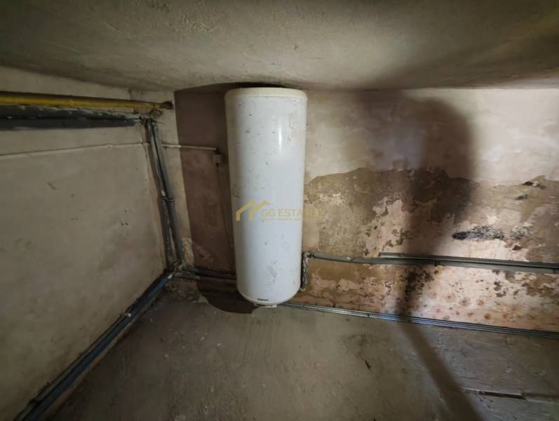 Wassertank im Einfamilienhaus mit abgenutzter Wand und Leitungen.