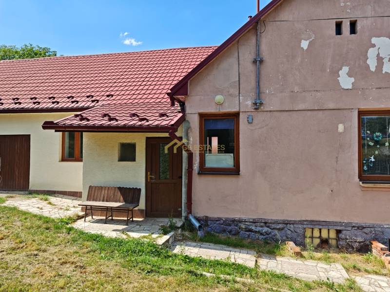 Ein Einfamilienhaus in der Dlhá-Straße in Vranov nad Topľou mit einem roten Dach und einer Bank.