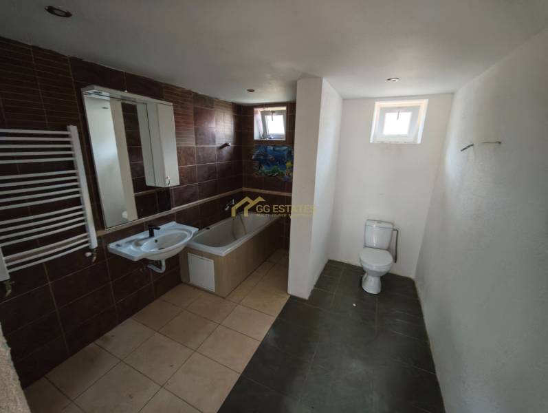 Badezimmer in einem Einfamilienhaus mit Badewanne, Toilette und Waschbecken, braune Fliesen.
