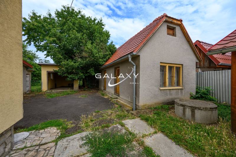 Ein Einfamilienhaus in Vidiná mit Höfen, Bäumen und Gebäuden im Hintergrund.