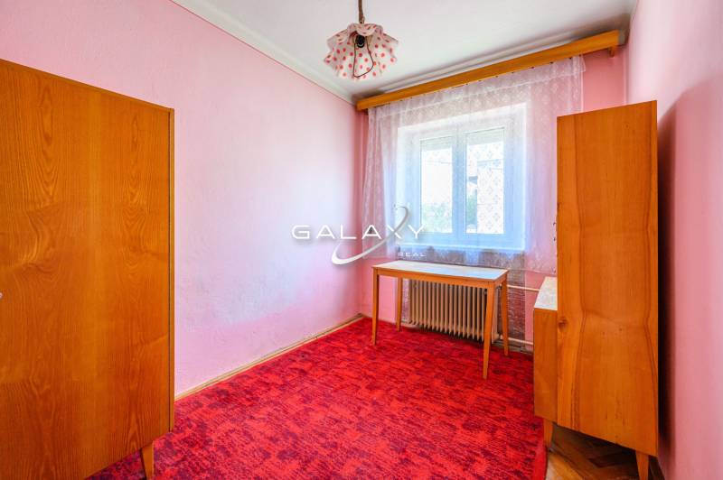 Ein Zimmer in einem Einfamilienhaus mit rosa Wänden, Möbeln und einem roten Teppich.