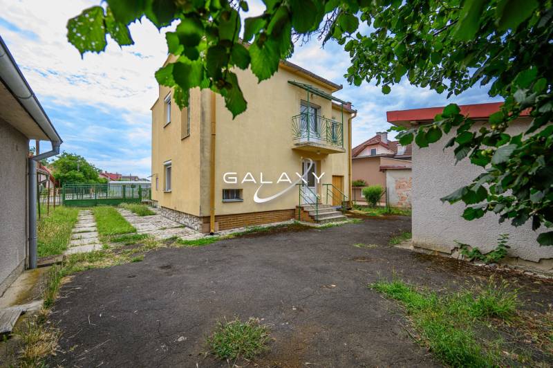 Ein Einfamilienhaus in Vidiná mit Garten, Rasen und umliegenden Gebäuden.
