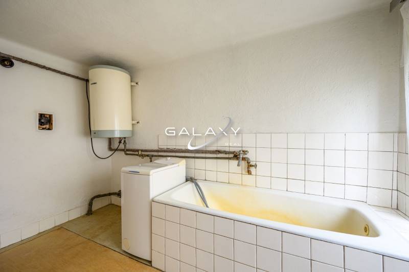 Badezimmer im Einfamilienhaus mit Badewanne, Boiler und Waschmaschine.