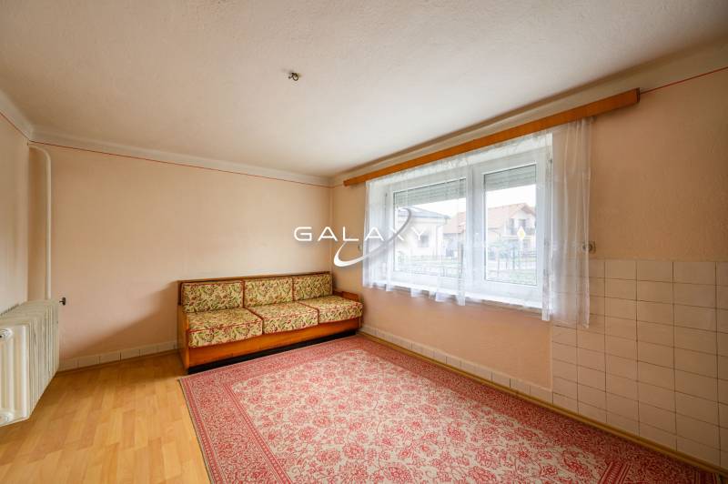 Ein Zimmer in einem Einfamilienhaus mit Teppich, Sofa und großem Fenster.