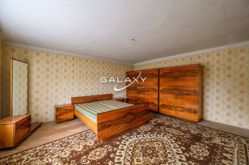 Schlafzimmer im Einfamilienhaus mit Holzmöbeln und Retro-Mustern an den Wänden.