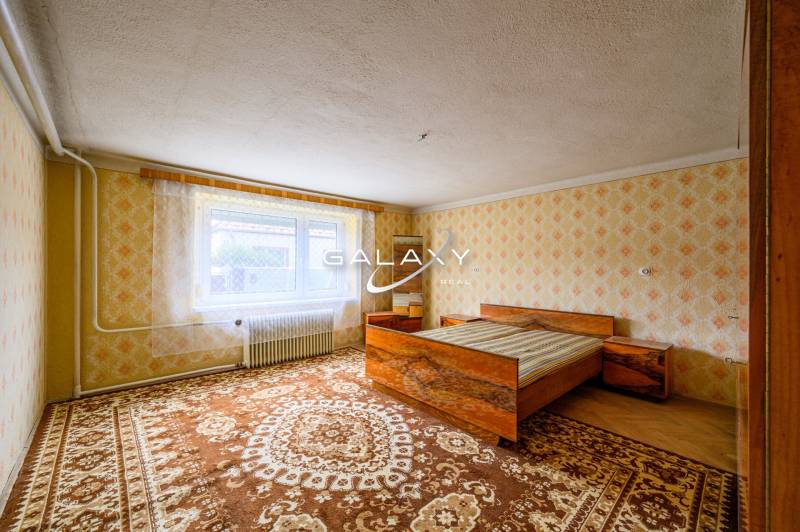 Schlafzimmer mit Bett, gemusterten Tapeten und Teppichen in einem Einfamilienhaus.