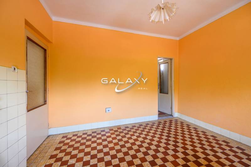Ein Zimmer in einem Einfamilienhaus mit orangefarbenen Wänden und einem Fliesenmuster auf dem Boden.