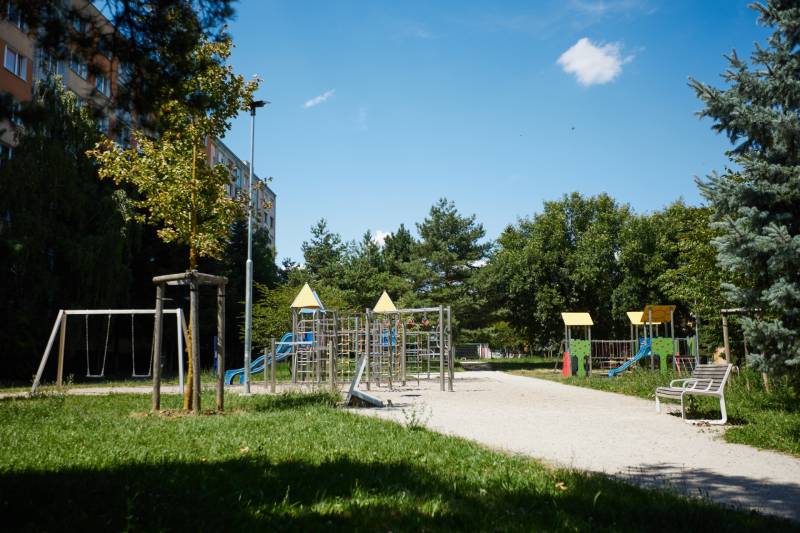 Ein Kinderspielplatz umgeben von Grünflächen und Plattenbauten, Košice - Stadtteil Juh.