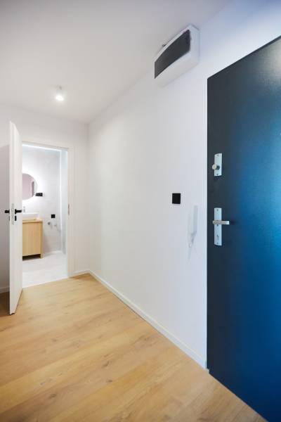 Eingangshalle in einer 2-Zimmer-Wohnung mit Holzboden und Badezimmer im Hintergrund.
