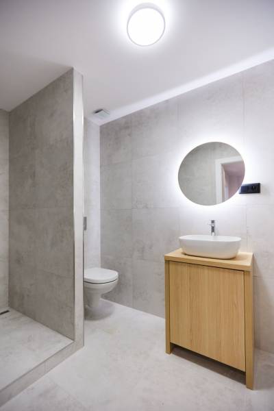 Badezimmer in einer 2-Zimmer-Wohnung mit Waschbecken, Spiegel und Duschkabine.