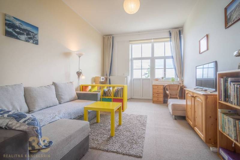Wohnzimmer mit hellem Sofa und gelbem Tisch in einer 3-Zimmer-Wohnung.