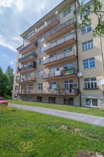 Ein fünfstöckiges Wohnhaus in der Hohen Tatra mit Balkonen und einem grünen Rasen.