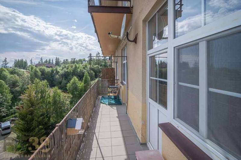 Balkon einer 3-Zimmer-Wohnung in der Hohen Tatra mit Blick auf Grünflächen und den Himmel.