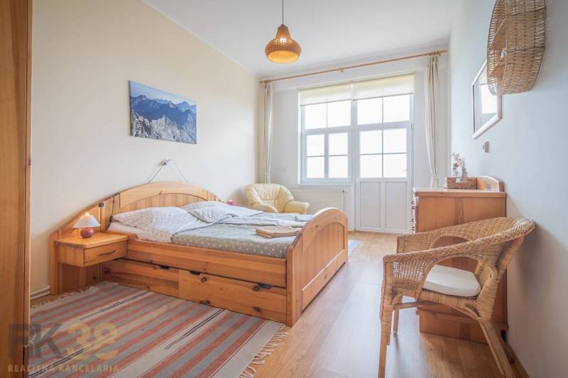 Helles Schlafzimmer mit Holzmöbeln und einem Korbsessel in einer 3-Zimmer-Wohnung.