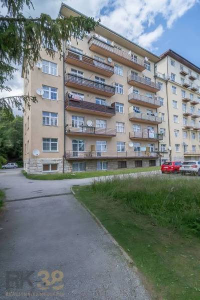Ein Wohnhaus in der Hohen Tatra mit Balkonen und einem Parkplatz vor dem Gebäude.