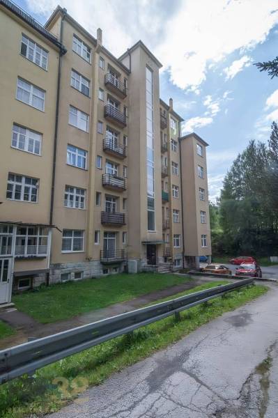 Ein fünfstöckiges Wohngebäude in der Hohen Tatra mit Zufahrtsstraße und Parkmöglichkeiten.