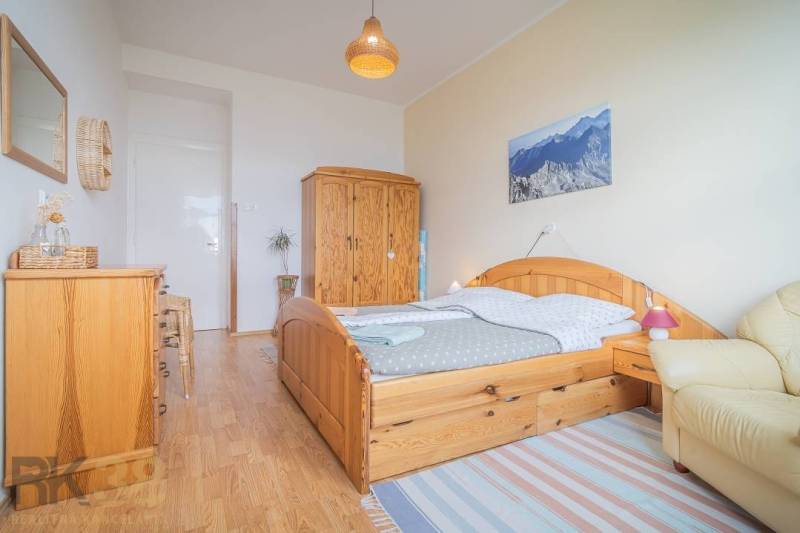 Schlafzimmer mit Holzmöbeln, einem Bild von Bergen und Korbdekorationen in einer 3-Zimmer-Wohnung.