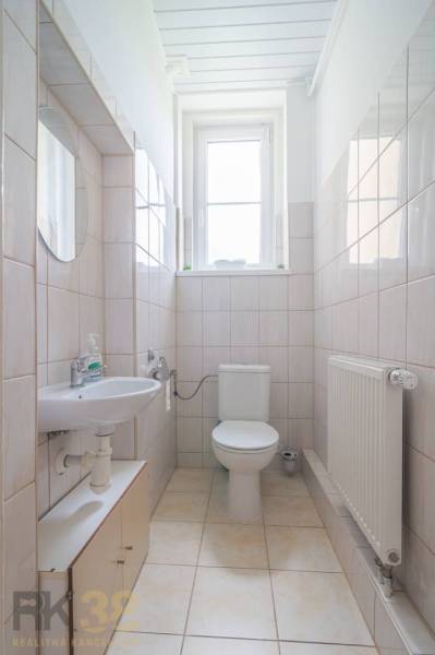 Badezimmer in einer 3-Zimmer-Wohnung mit Waschbecken, Toilette, Heizkörper und Fenster.