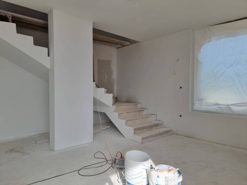 Die Treppe in der Villa während der Renovierung, neben einem großen Fenster mit verdeckter Aussicht.