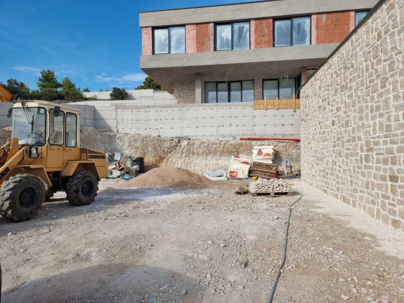 Baustelle mit einer im Bau befindlichen Villa in der Stadt Vodice, sichtbar sind eine Baumaschine und Material.