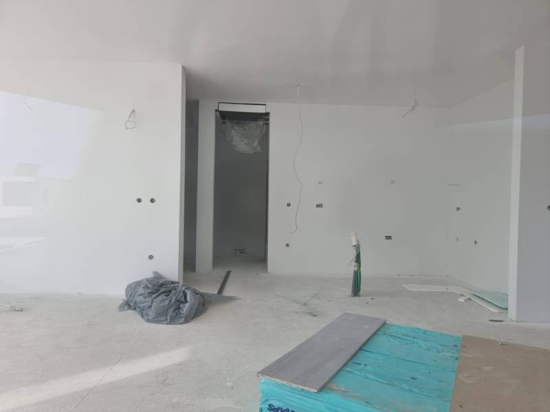 Ein unfertiger Raum in einer Villa mit weißen Wänden und einem unvollendeten Boden.