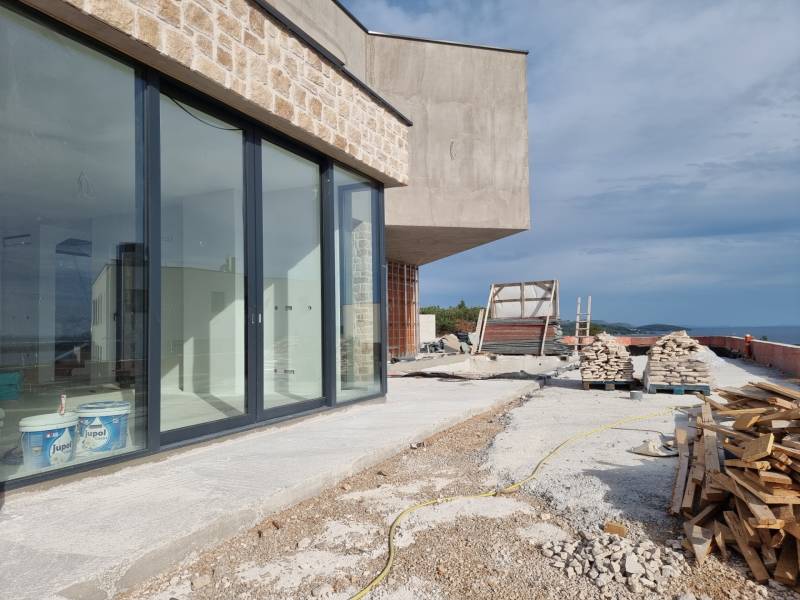 Der Bau einer Villa in Vodice mit einer verglasten Wand und einer Baustelle an der Küste.