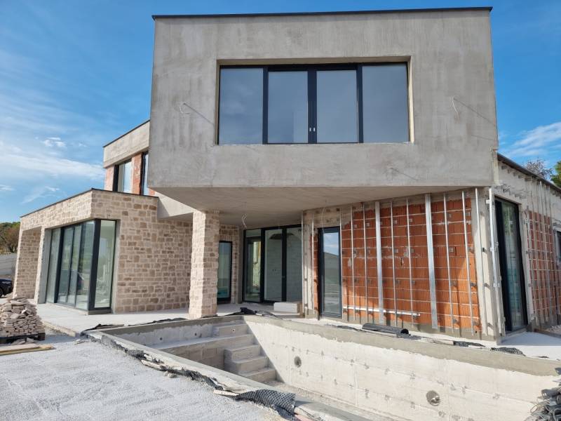 Unvollendete Villa in der Stadt Vodice mit Stein- und Ziegelwänden, großen Fenstern und einer Terrasse.