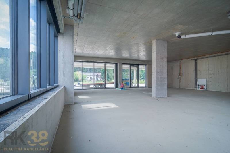Ungeordnete Geschäftsräume mit Glastüren, hohen Decken und Blick nach außen.