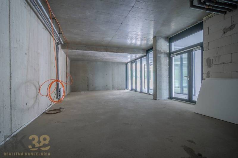 Innenraum von Geschäftsräumen mit Glaswand, Betondecke und Elektroinstallation.