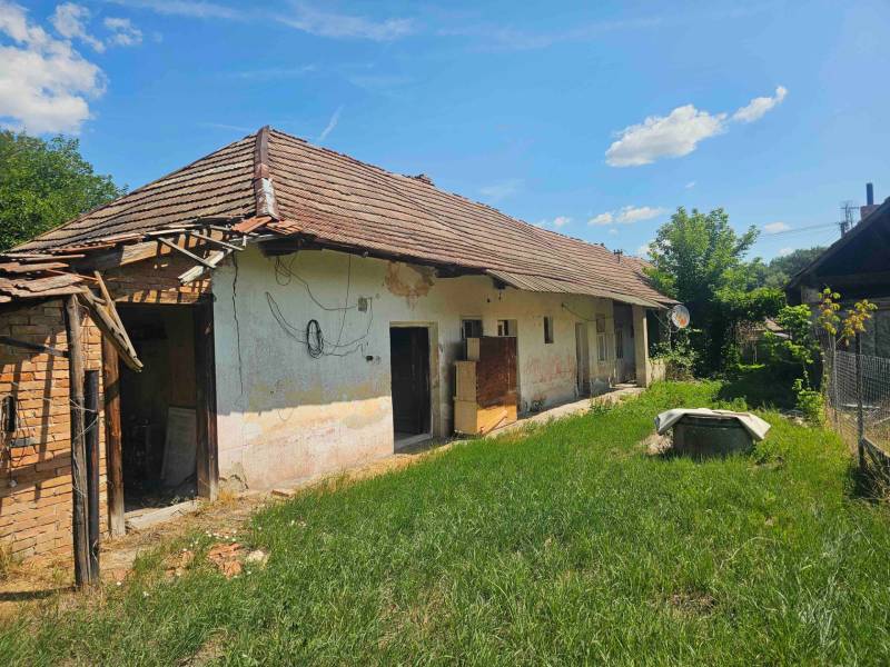 Ein Einfamilienhaus in Hronovce mit einer verlassenen Fassade, einem älteren Dach und einer grasbewachsenen Umgebung.