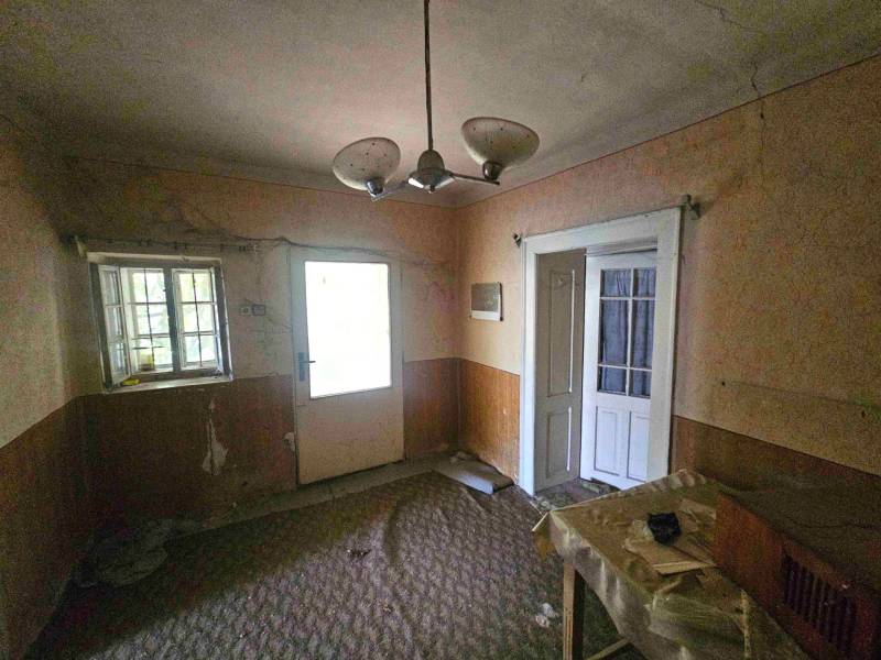 Ein verlassenes Zimmer in einem Einfamilienhaus mit sichtbaren Abnutzungserscheinungen, alter Beleuchtung und geschlossenen Türen.