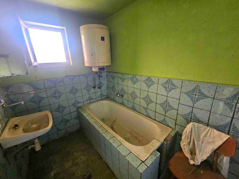 Badezimmer mit Badewanne und Waschbecken in einem Einfamilienhaus mit blauen Fliesen.