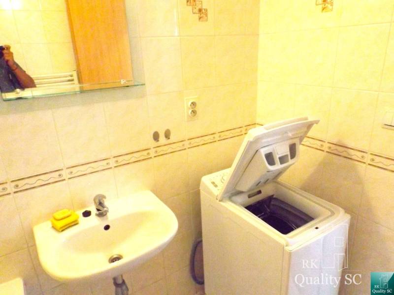 Badezimmer mit Waschmaschine und Waschbecken in einer Einzimmerwohnung, einfaches Design.