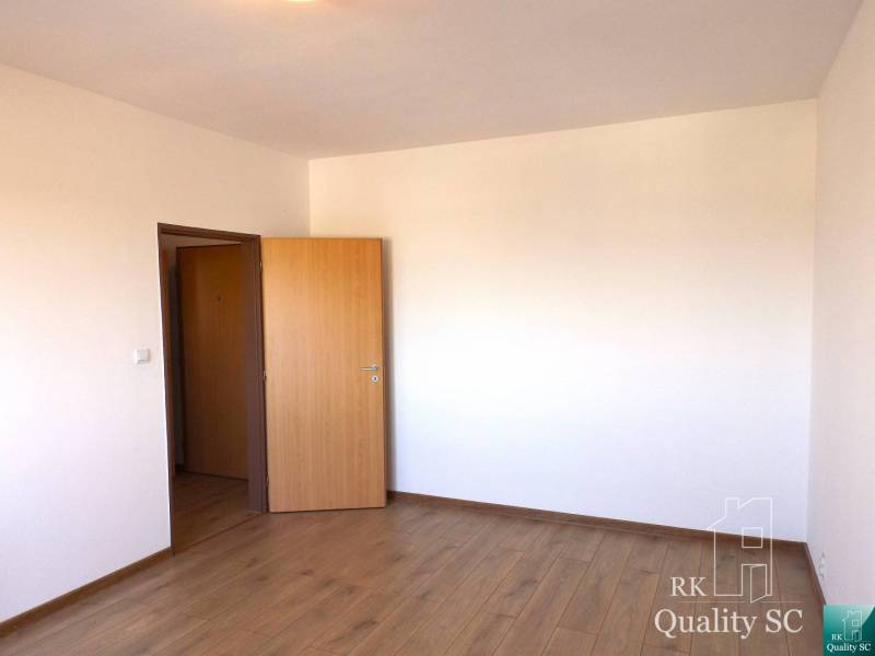 Ein Zimmer in einer Einzimmerwohnung mit Holzboden und offener Tür.