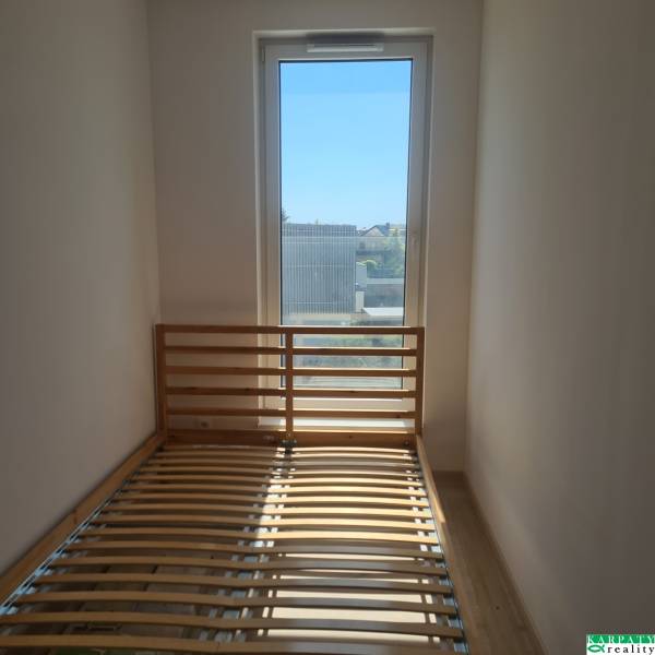 Helles Zimmer in einer Einzimmerwohnung mit Bett und großem Fenster.