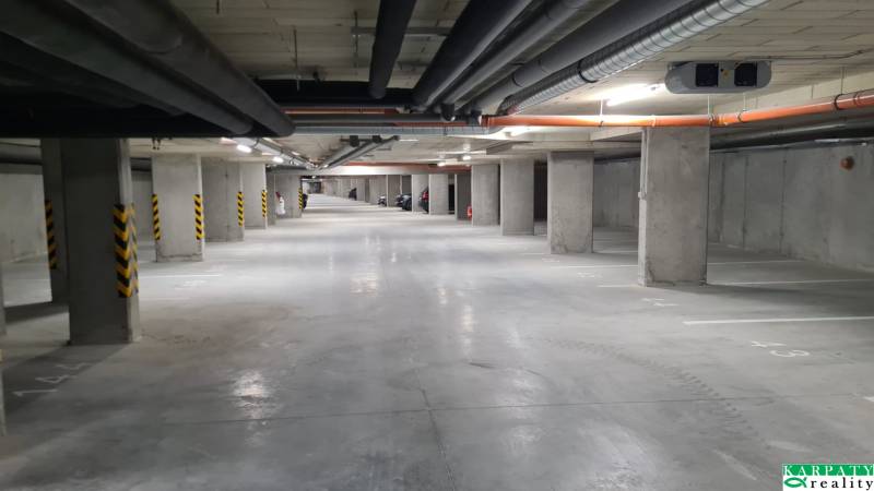 Unterirdische Garage mit Parkplätzen und Betonpfeilern in einer Einzimmerwohnung.