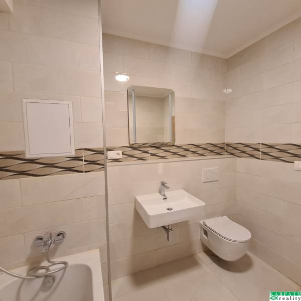 Badezimmer mit Spiegel, Waschbecken und Toilette in einer Einzimmerwohnung.