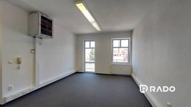 Ein geräumiges Büro mit Fenstern, einer hellen Decke und Steckdosen, ideal für produktive Arbeit.