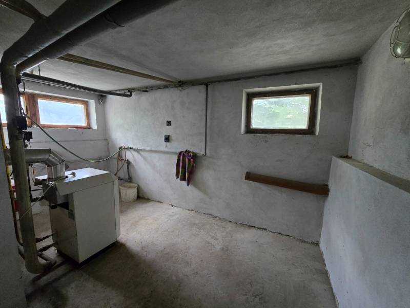 Heizraum in einem Einfamilienhaus mit Kessel, Rohrleitungen und kleinen Fenstern.