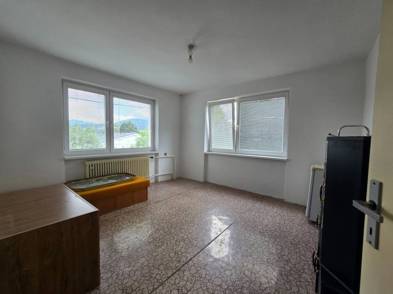 Einfaches Zimmer in einem Einfamilienhaus mit Blick durch große Fenster.