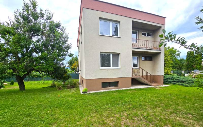 Ein Einfamilienhaus in Nové Mesto nad Váhom mit Garten und Bäumen auf einer Rasenfläche.