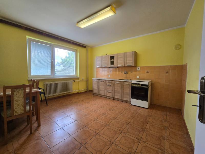 Eine Küche in einem Einfamilienhaus mit gelben Wänden, Holzmöbeln und Keramikfliesen.