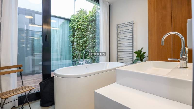 Badezimmer in einem Einfamilienhaus mit Badewanne, Pflanze und großem Fenster.