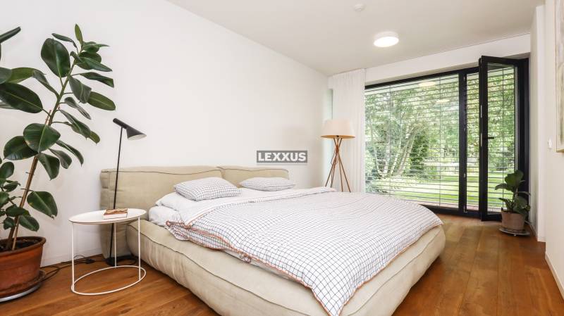 Schlafzimmer im Einfamilienhaus mit Bett, Pflanzen und Blick in den Garten.