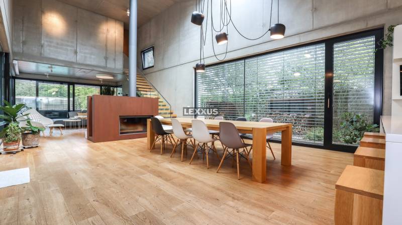 Ein Interieur eines Einfamilienhauses mit einem großen Tisch, einem Kamin und viel natürlichem Licht.