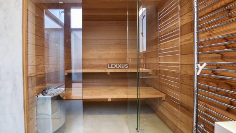 Holzsauna mit Glastüren und Bänken im Einfamilienhaus.