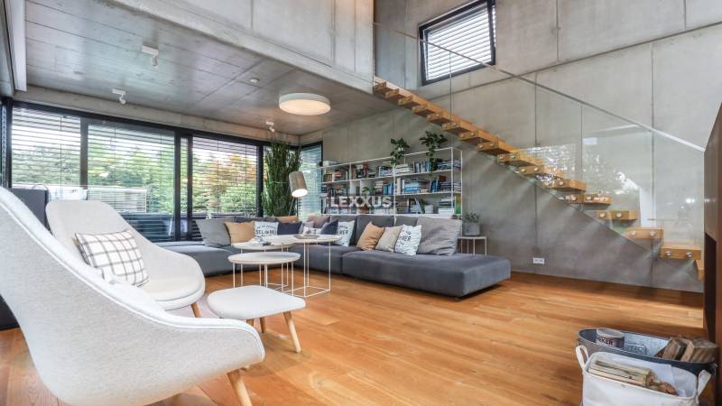 Ein stilvolles Wohnzimmer mit Holzboden, Treppe und großen Fenstern in einem Einfamilienhaus.