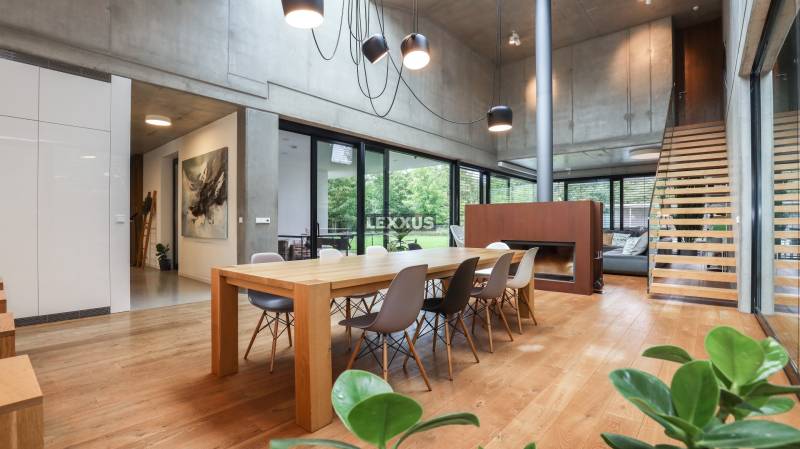 Esszimmer in einem Einfamilienhaus mit großem Holztisch, Kamin und moderner Beleuchtung.