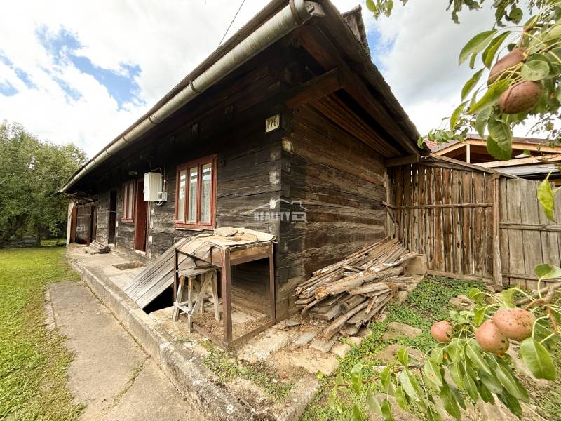 Holzhütte in Papradno mit einem Holzvorrat und Obstbäumen im Hof.