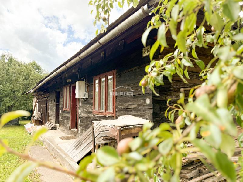 Eine Holzhütte in Papradno, umgeben von Natur, mit ländlicher Atmosphäre und grünem Rasen.